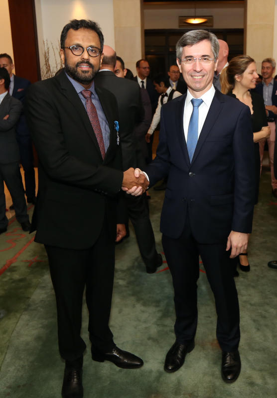 George (left) shaking hands with Laplanche after receiving the National Order of Merit. 