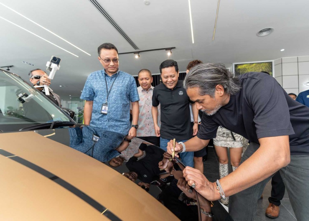 Khairy signing on the bonnet of the Final Edition with Rizal (second from right) looking on.